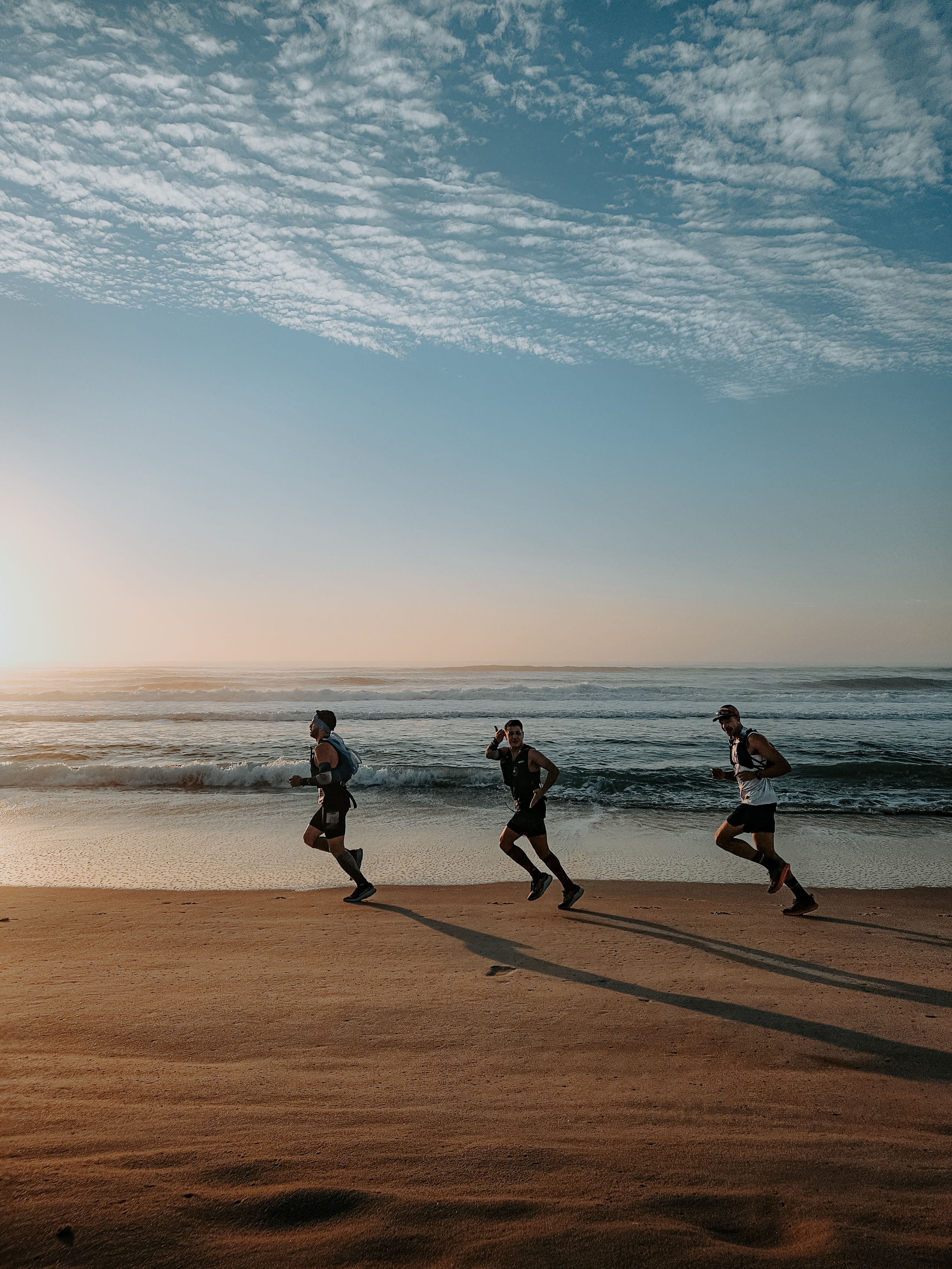 Three runners sharing a run along the beach